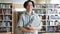 Portrait of male student holding books in school library with happy face