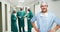 Portrait of male surgeon standing with hands on hips
