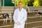 Portrait of male veterinarian who is standing at her workplace near cows at farm outdoors