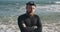 Portrait of man with beard on background of sea waves. Adult serious man swimmer looking into the frame. Young single