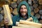 Portrait of a man with a bunch of chopped firewood. Bearded lumberjack with firewood for the fireplace.