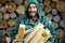 Portrait of a man with a bunch of chopped firewood. Bearded lumberjack with firewood for the fireplace.