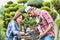 Portrait of man carrying pot while beautiful gardener checking plants in the garden