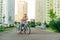 Portrait of a man with a city bike on the background of a row of bicycles for sharing and cityscape, standing on the path and