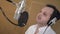 Portrait of man emotionally sing in headphones in front of microphone. Studio