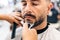 Portrait of a man with eyes closed being shaved in a barbershop