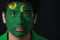 Portrait of a man with the flag of the Cocos Keeling Islands painted on his face on black background.