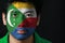 Portrait of a man with the flag of the Comoros painted on his face on black background.