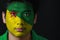 Portrait of a man with the flag of the French Guiana painted on his face on black background.