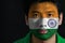 Portrait of a man with the flag of the India painted on his face on black background.