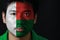 Portrait of a man with the flag of the Madagascar painted on his face on black background.