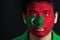 Portrait of a man with the flag of the Maldives painted on his face on black background.