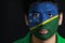 Portrait of a man with the flag of the Solomon Islands painted on his face on black background.