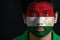 Portrait of a man with the flag of the Tajikistan painted on his face on black background.