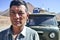 Portrait of man in front of Soviet old van in Pamir mountains