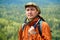 Portrait of a man geologist with a backpack and a geological hammer against the wooded mountain landscape