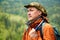 Portrait of a man geologist with a backpack and a geological hammer against the wooded mountain landscape