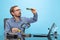 Portrait of man in glasses and checkered shirt attentively looking at motherboard isolated over blue background