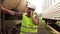 Portrait of a man in glasses worker in a helmet and uniform, walking on the train station talking on the phone