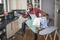 Portrait of man holding laundry basket and iron while closing dishwasher in kitchen