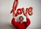 Portrait of man holding up a balloon in the shape of the word love on white background. Valentine`s Day Celebration