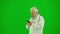 Portrait of man medic on chroma key green screen. Close side view senior doctor in white coat walking texting on