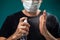 A portrait of man with medical face mask using disinfectant spray on hands. People, medicine, healthcare concept. Coronavirus