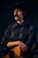 Portrait of man with moustaches in stylish big scarf and vintage hat posing with guitar isolated over dark blue
