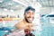 Portrait, man and relax in swimming pool with cap in sports wellness, training or exercise for body healthcare. Workout