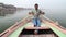 Portrait of man rowing in boat at Ganges, with cityscape in background.