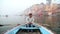 Portrait of man rowing in boat at Ganges, with Varanasi cityscape in background.