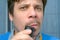 Portrait of man shaving forming moustache using electric razor in bathroom.