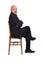 Portrait of a man sitting on a chair side view and looking at camera on  white background