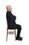 Portrait of a man sitting on a chair side view on  white background, arms crossed