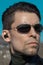 Portrait of a man with a smooth haircut and dark sunglasses looking like a secret agent or character from the movie The Matrix