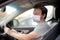 Portrait of man wearing disposable medical facemask in a car during coronavirus outbreak