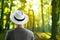 Portrait of man with white hat from the back with summer travel green orange forest nature background