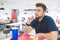 Portrait of a man who eats French fries in a light restaurant of fast food and looks to the side