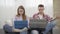 Portrait of man and woman absorbed with online communication. Young Caucasian redhead girl and brunette guy using social