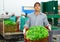 Portrait of man working on sorting line at vegetable warehouse, stacking boxes with lettuce