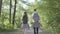 Portrait man and young cute girl walking in the forest. Pair of travelers with backpacks outdoors. Leisure couples