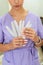 Portrait of a manicurist young girl holding nail file for processing nails, wearing purple uniform. Manicure and