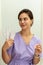 Portrait of a manicurist young girl holding nail file for processing nails, wearing purple uniform. Manicure and