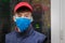 Portrait of a masked teenager in close-up. A technician in a red cap and medical mask is in the server room. The specialist is in