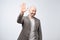 Portrait of a mature bald man in suit wave hand welcome. Human emotion expression and lifestyle concept.