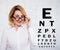 Portrait of mature business woman in eyeglasses and eyevision test chart over white wall