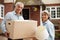 Portrait Of Mature Couple Carrying Boxes On Moving Day In Front Of Dream Home