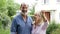 Portrait of mature couple standing in garden in front of dream home in countryside holding keys