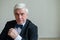 Portrait of a mature gray-haired smiling man in a suit and bow-tie. An elegantly dressed, clean-shaven senior looks