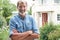 Portrait Of Mature Man Standing In Garden In Front Of Dream Home In Countryside